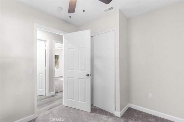 unfurnished bedroom featuring ceiling fan, light colored carpet, and a closet