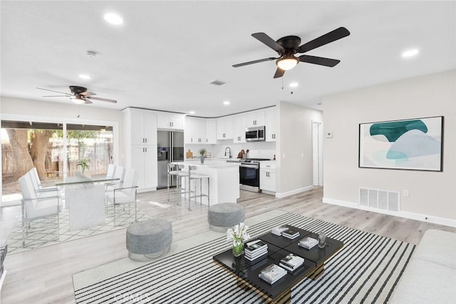 living room with ceiling fan and light hardwood / wood-style floors