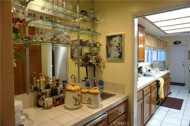 bar featuring tile countertops, light tile patterned floors, and black dishwasher