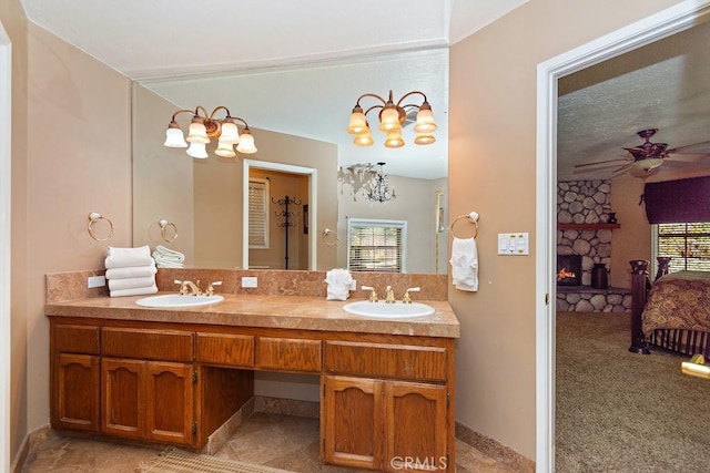 bathroom with ceiling fan, a healthy amount of sunlight, a fireplace, and vanity