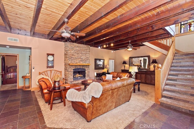 living room featuring ceiling fan, a fireplace, beamed ceiling, and wood ceiling