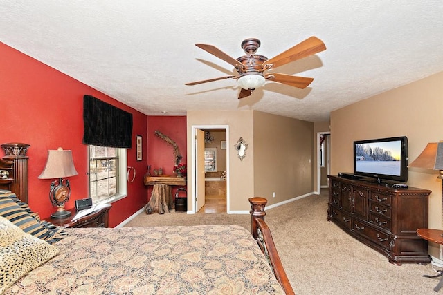 bedroom with a textured ceiling, ceiling fan, light carpet, and ensuite bath