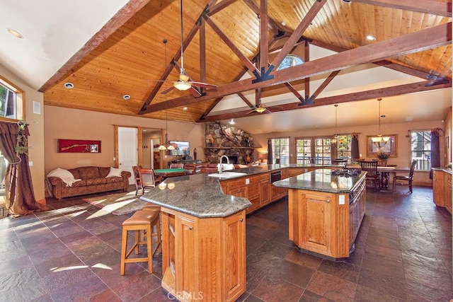 kitchen featuring kitchen peninsula, pendant lighting, a large island with sink, a fireplace, and a breakfast bar area