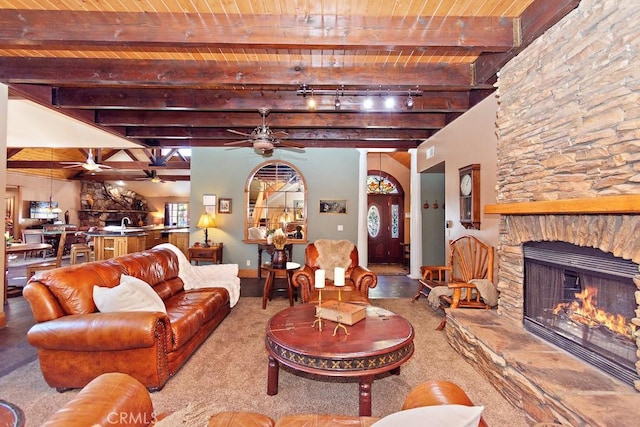 living room with beamed ceiling, carpet flooring, a stone fireplace, and wood ceiling