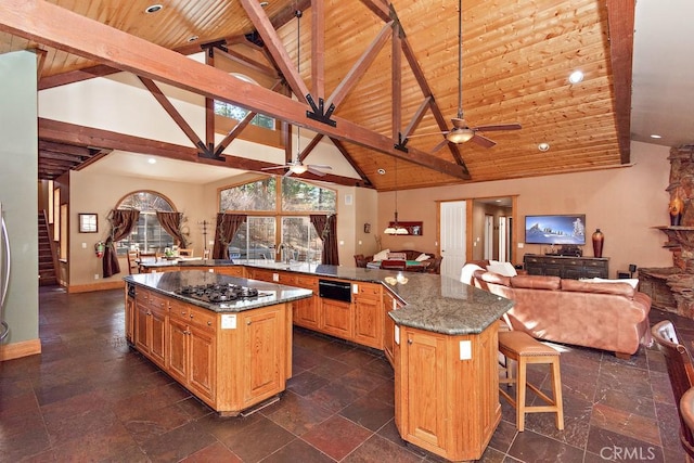 kitchen with wooden ceiling, high vaulted ceiling, dark stone counters, a breakfast bar area, and a kitchen island