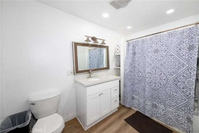 bathroom featuring walk in shower, hardwood / wood-style floors, vanity, and toilet