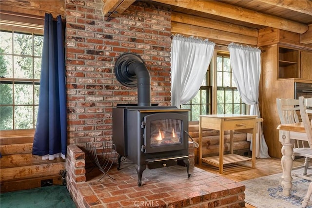 living area featuring hardwood / wood-style flooring, beam ceiling, a wood stove, and a wealth of natural light