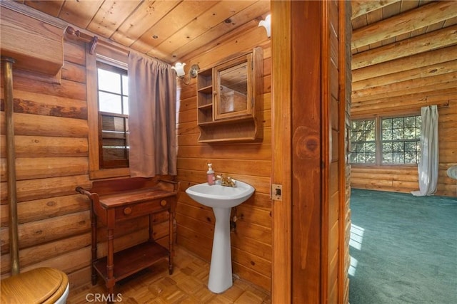 bathroom featuring toilet, wooden ceiling, and log walls