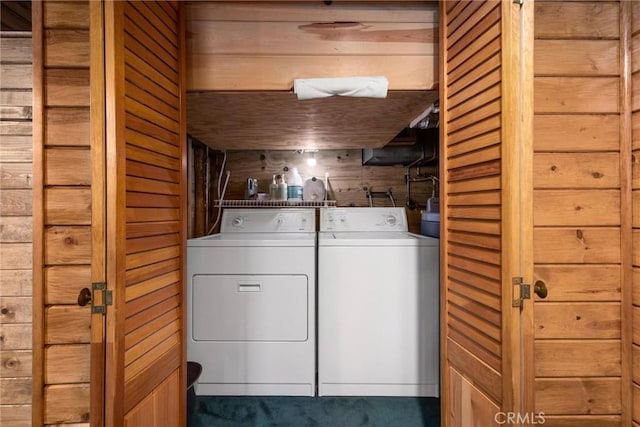 laundry room with wood walls and washing machine and clothes dryer