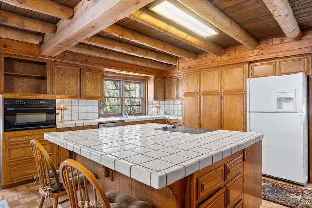 kitchen with black appliances, beamed ceiling, tile counters, a kitchen island, and wood ceiling