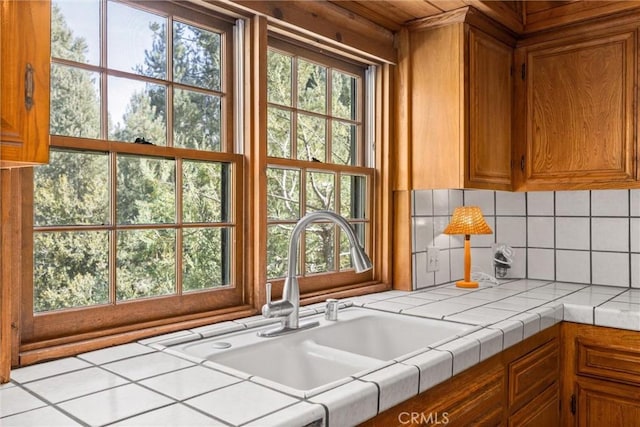 interior space featuring a sink, tile countertops, brown cabinets, and a healthy amount of sunlight