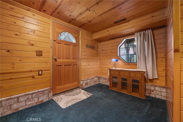 carpeted entrance foyer featuring wooden ceiling and wood walls