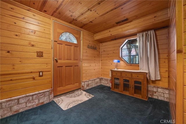 foyer entrance featuring wooden walls, carpet floors, wooden ceiling, a healthy amount of sunlight, and visible vents