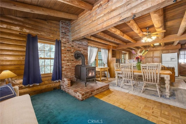living room with wooden ceiling, a wood stove, beam ceiling, and a wealth of natural light