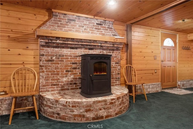 living area featuring carpet flooring, a wood stove, wood walls, and wood ceiling