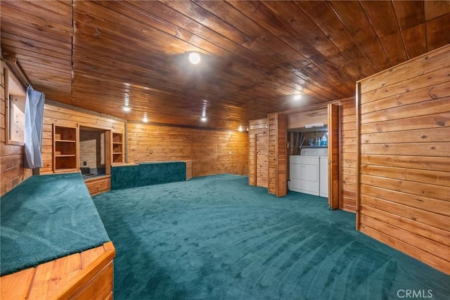 interior space featuring dark colored carpet, wooden ceiling, wooden walls, and washing machine and clothes dryer