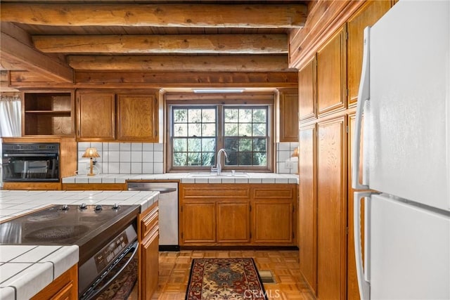 kitchen featuring oven, a sink, dishwasher, stove, and freestanding refrigerator