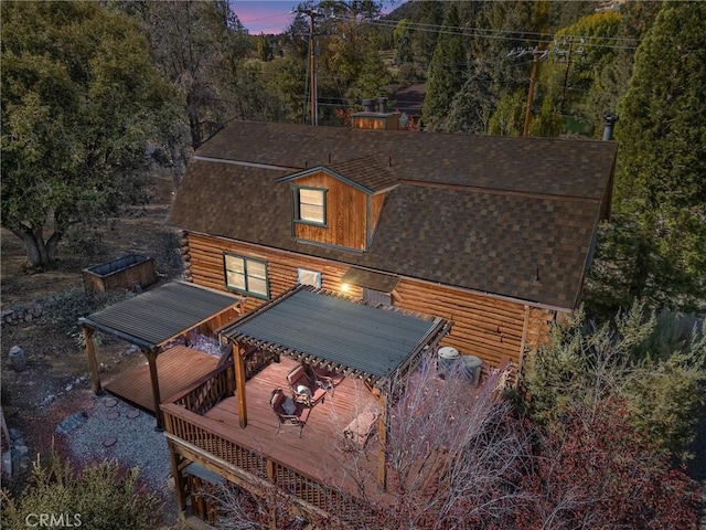 back house at dusk featuring a wooden deck