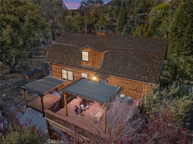 exterior space featuring a deck, log siding, and a shingled roof