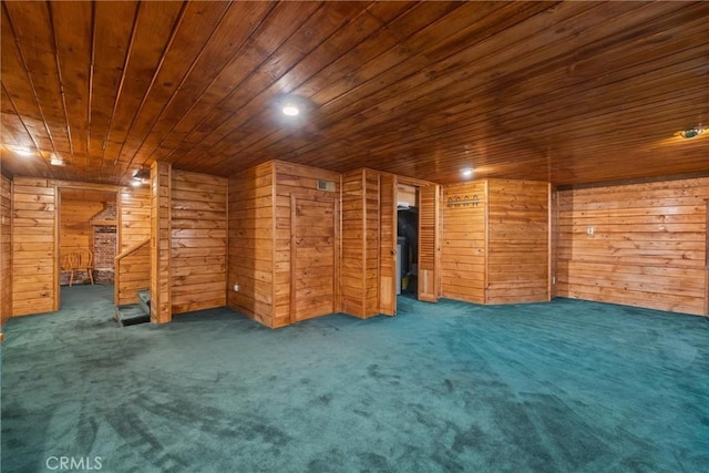 unfurnished living room featuring carpet flooring, wood ceiling, and wood walls
