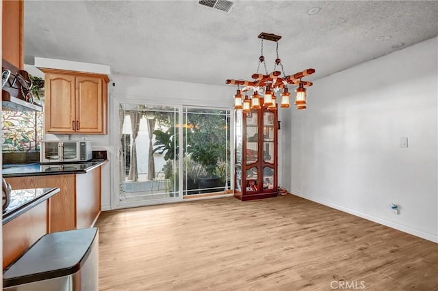 kitchen with a chandelier, pendant lighting, light hardwood / wood-style floors, and a textured ceiling