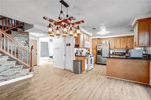 kitchen with light hardwood / wood-style floors, a textured ceiling, decorative light fixtures, white appliances, and ceiling fan with notable chandelier