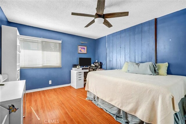 bedroom with ceiling fan, hardwood / wood-style floors, and a textured ceiling