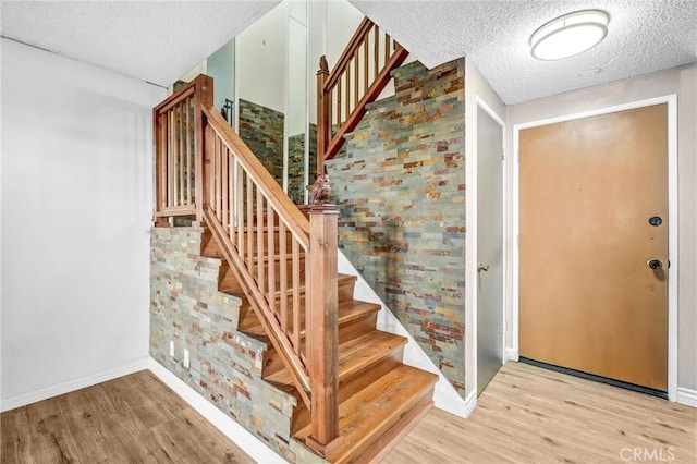 stairs featuring wood-type flooring and a textured ceiling