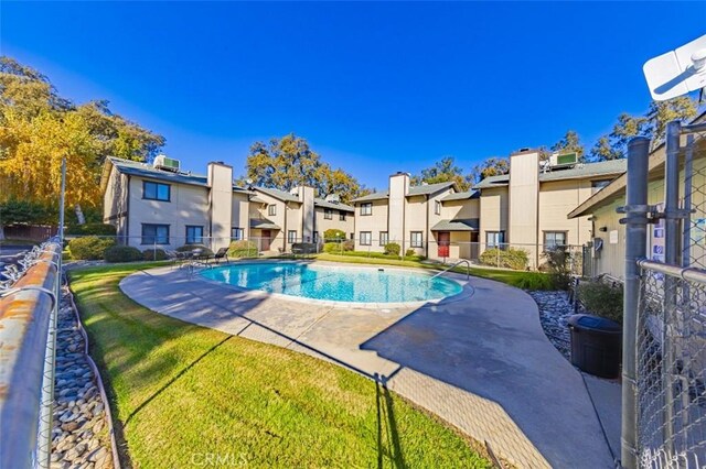 view of pool with a lawn and a patio