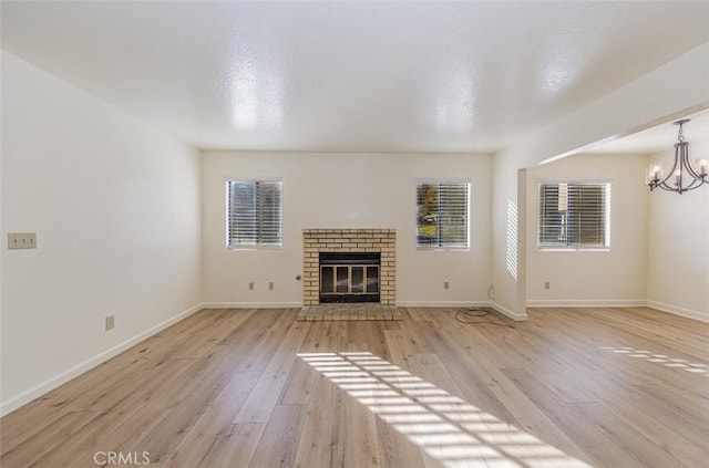 unfurnished living room featuring a chandelier, a fireplace, and light hardwood / wood-style flooring