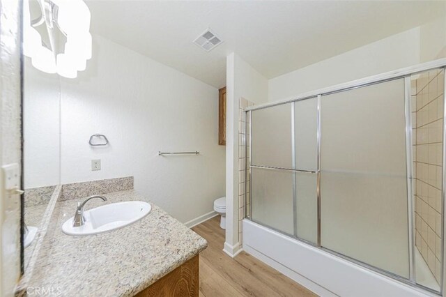 full bathroom featuring a notable chandelier, toilet, shower / bath combination with glass door, vanity, and hardwood / wood-style flooring