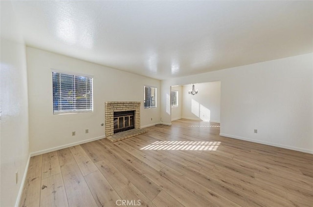 unfurnished living room featuring a notable chandelier, light hardwood / wood-style floors, and a fireplace