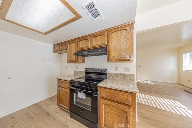 kitchen with light stone countertops, light wood-type flooring, a textured ceiling, and black electric range