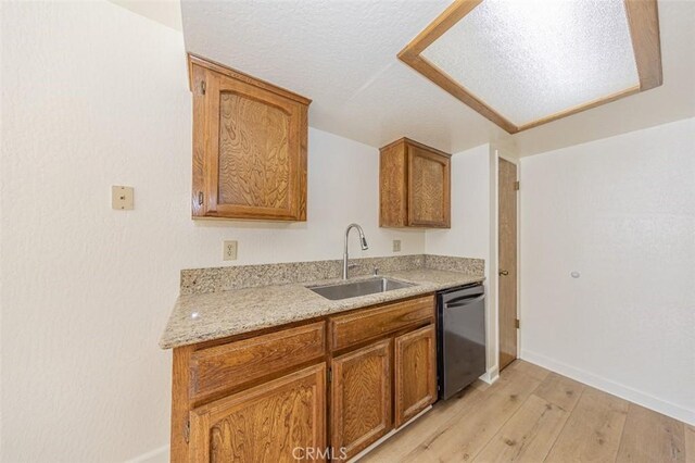 kitchen with light stone countertops, light wood-type flooring, a textured ceiling, sink, and dishwasher