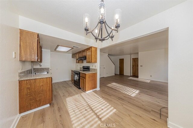 kitchen featuring sink, electric range, decorative light fixtures, a notable chandelier, and light hardwood / wood-style floors