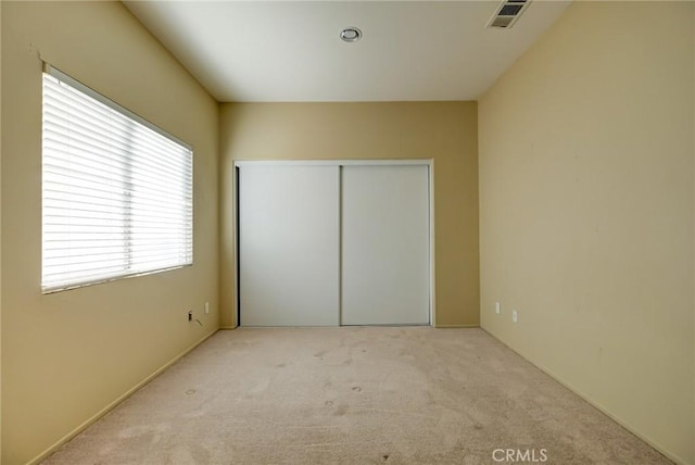 unfurnished bedroom with light colored carpet and a closet