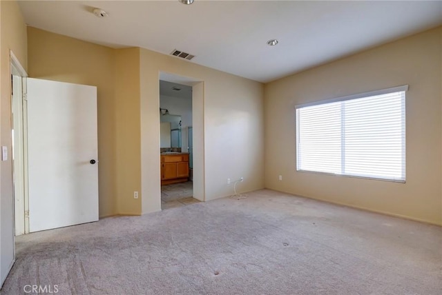 unfurnished bedroom with light colored carpet and ensuite bath