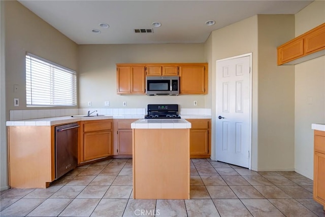 kitchen with sink, stainless steel appliances, a kitchen island, and light tile patterned flooring