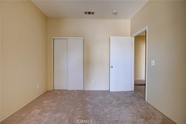 unfurnished bedroom with light carpet and a closet