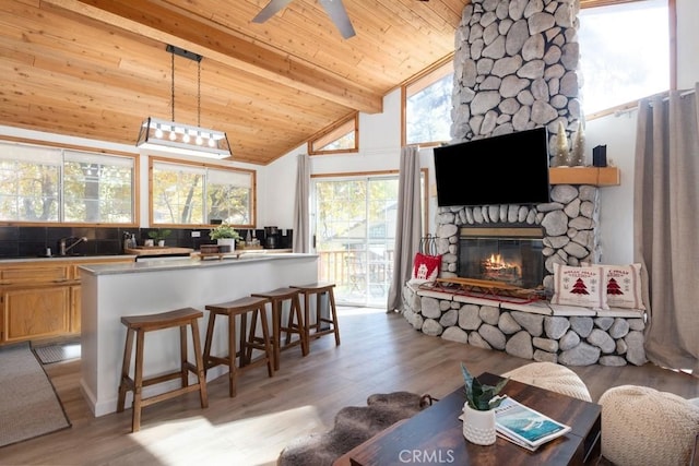 kitchen with light hardwood / wood-style flooring, wooden ceiling, beamed ceiling, a fireplace, and hanging light fixtures