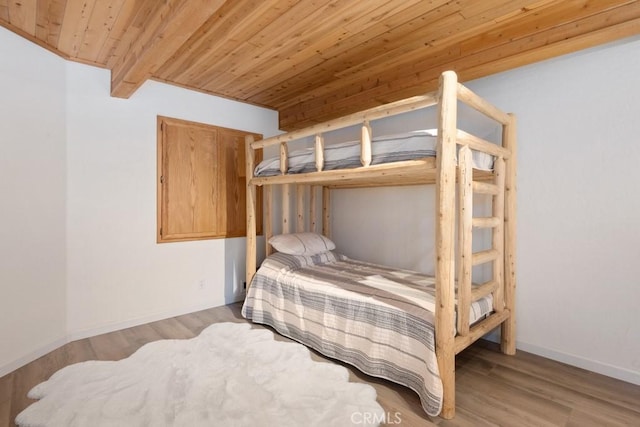 bedroom featuring hardwood / wood-style flooring, wooden ceiling, and beamed ceiling