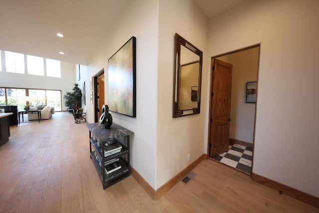 hallway featuring light hardwood / wood-style flooring and a high ceiling