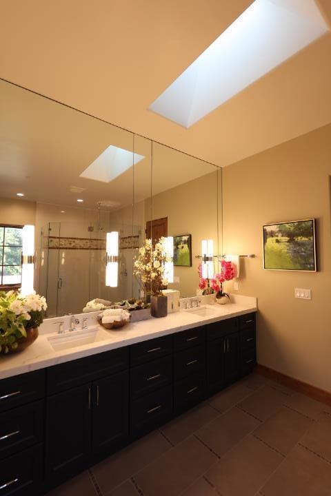 bathroom with tile patterned floors, a skylight, vanity, and an enclosed shower