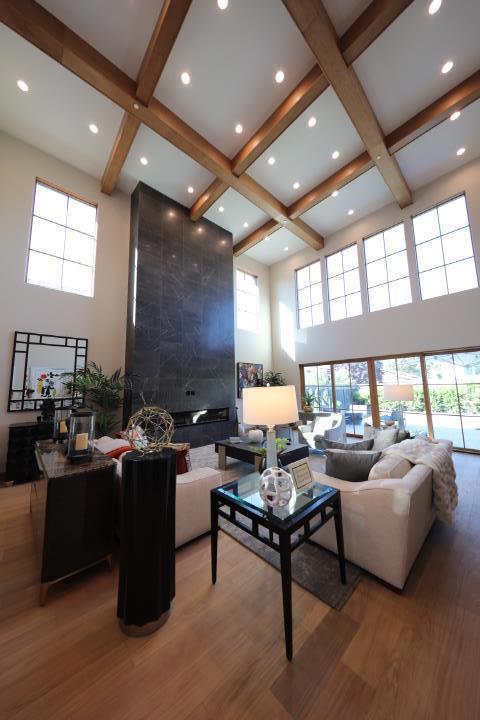 living room with beamed ceiling, a high ceiling, and hardwood / wood-style flooring