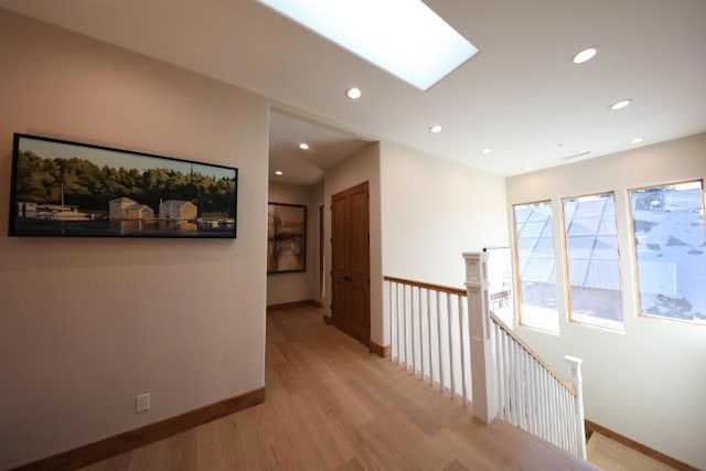 corridor with light hardwood / wood-style floors and a skylight