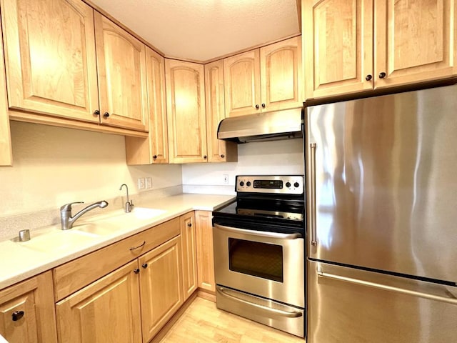 kitchen featuring light brown cabinets, sink, light wood-type flooring, a textured ceiling, and appliances with stainless steel finishes