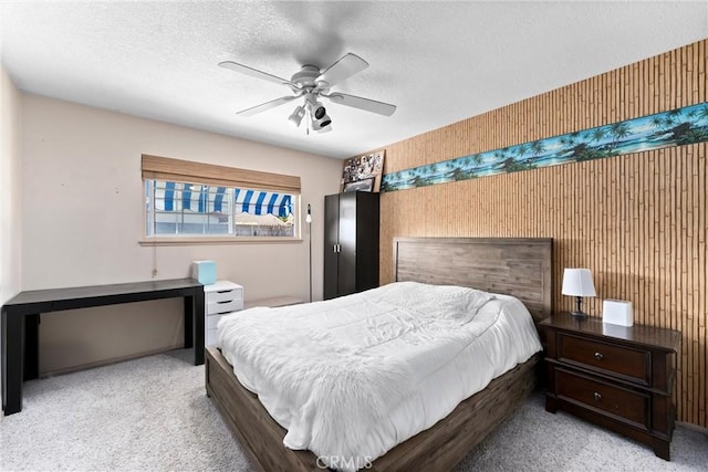 carpeted bedroom featuring ceiling fan and a textured ceiling