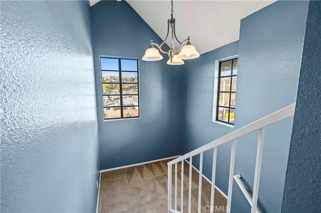 staircase featuring plenty of natural light, vaulted ceiling, and a notable chandelier