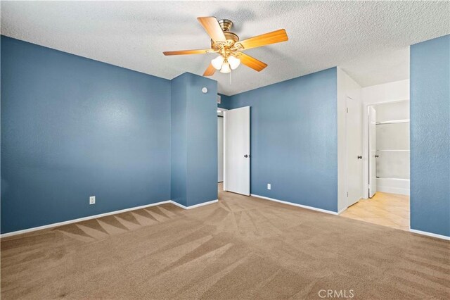 spare room with light carpet, ceiling fan, and a textured ceiling