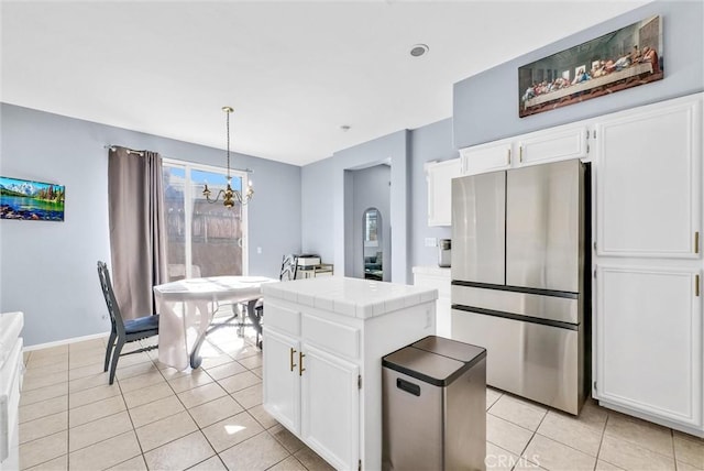 kitchen featuring stainless steel refrigerator, white cabinetry, tile counters, hanging light fixtures, and an inviting chandelier